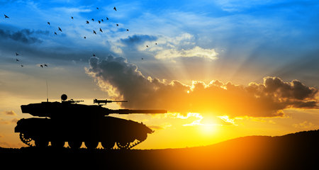 Silhouette of army tank at sunset sky background. Military machinery.の写真素材