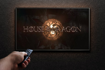 House of the Dragon trailer or movie on TV screen. Man turns on TV with remote control.のeditorial素材
