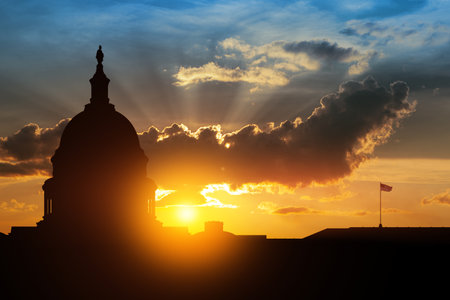 The United States Capitol building silhouette on background of sky at sunset with flying birds in Washington DC, USA.の写真素材