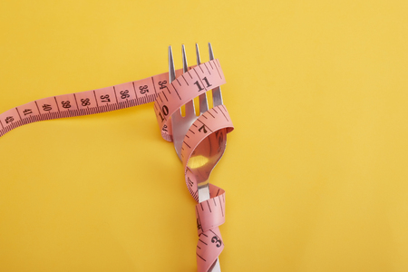 healthy eating, drinks, diet, detox and people concept -Measure tape roll on fork with isolated colour.の写真素材
