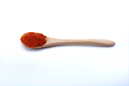 Chili powder with wooden spoon on white backgroundの写真素材