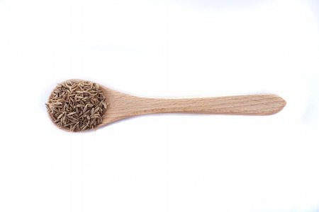 Close up pile of Cumin seeds isolated on white background with wooden spoonの写真素材