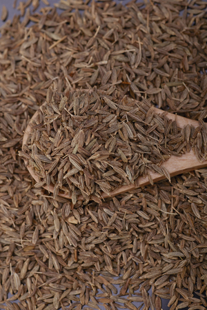 Cumin seed  over Black background with wooden spoon. Top view