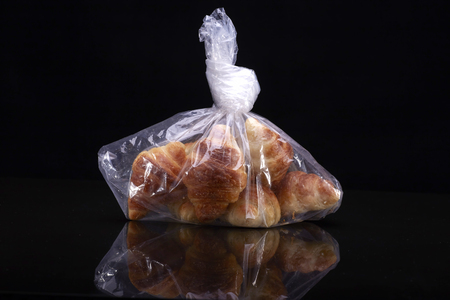 Tasty croissants with plastic bag over  black backgoundの写真素材