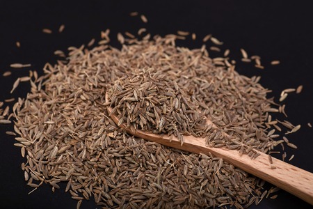 Cumin seed  over Black background with wooden spoonの写真素材