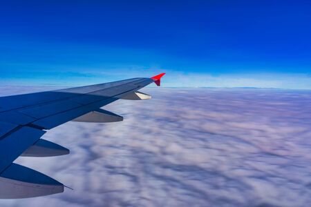 The passenger plane transports passengers in the air, looking out from the glass window of the plane while traveling, and the wing flies in the beautiful clouds of the sky.の写真素材