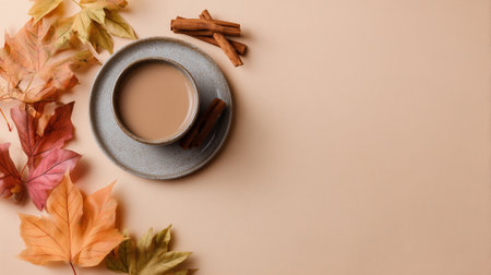 Cup of coffee with autumn leaves and cinnamon on beige backgroundの素材