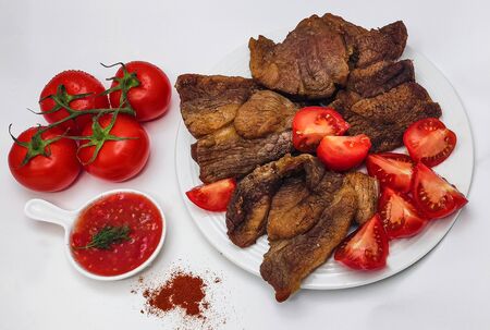 Roast beef. Pieces of juicy meat with tomatoes and sauce with spices. Delicious Breakfast, lunch or dinnerの写真素材