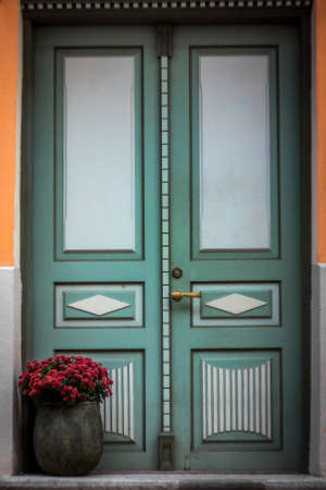 In the center of the old European city is an old wooden front door on the porch of the house with cracked paint.の写真素材
