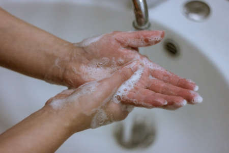 To prevent a coronavirus pandemic, a girl washes her hands with soap and water, proper washing and...