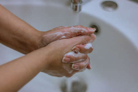 To prevent a coronavirus pandemic, a girl washes her hands with soap and water, proper washing and handling of an antiseptic will protect against the virus.の写真素材