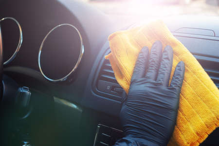 Cleaning car interior from coronovirus and pandemic with disinfectant fluid. Hands in rubber...