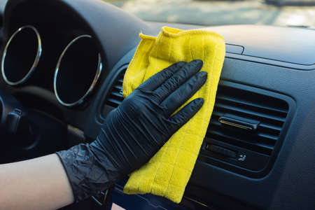 Cleaning car interior from coronovirus and pandemic with disinfectant fluid. Hands in rubber...