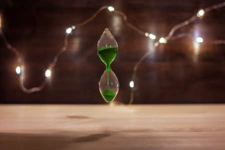 Hourglass soaring in the air, a symbol of freedom and weightlessness in modern life. Space concept and through green sandの写真素材