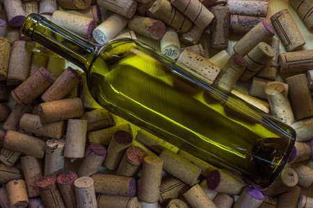 A bottle of wine without a label lies on a large number of wine corks. Cork tree and its texture for...