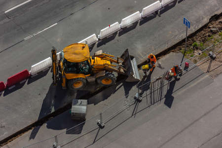Repair work on the city streets using a heavy loader with a bucket for the construction of the road....