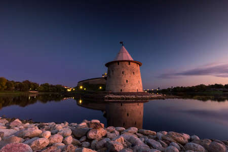 View of the night Pskov Kremlin near the city river on a summer clear day. Beautiful purple sunset over the cityscape.のeditorial素材