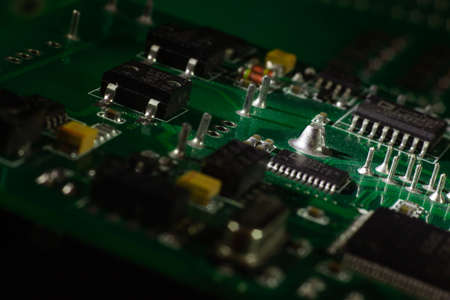Macro close-up shot of green circuit board, computer motherboard Components: microcircuits, processor, transistors, semiconductors. Inside an electronic device, parts of a supercomputer.の写真素材