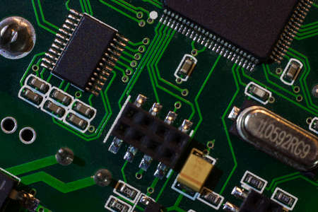 Fragment and components of a motherboard (PCB) of computer technology with many elements. Macro photography of processors and transistors. IT industry backgroundの写真素材