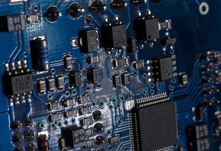 Close-up of a blue printed circuit board (PCB) with stripes of conductors between a transistor and an electronic equipment processor. IT technologies in programming, upgrade and abstract backgroundの写真素材