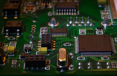 Macro close-up shot of green circuit board, computer motherboard Components: microcircuits, processor, transistors, semiconductors. Inside an electronic device, parts of a supercomputer.の写真素材