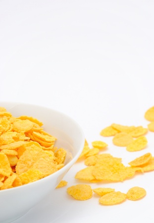 Gold corn flakes heaped in the white dish and on the white table.の写真素材
