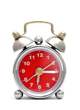Old metal alarm clock with red dial on the white background の写真素材
