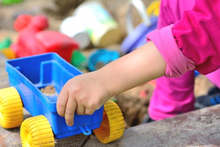 Children hand keep the plastic carriage toy at sandpit の写真素材