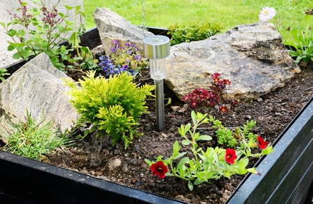 Ornamental flowerpot with flowers stones and solar lamp.の写真素材