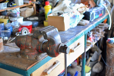 Messy table with old metal rusty vice and other working tools in the workshop.の写真素材