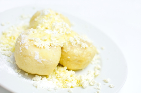 Fruit dumplings with fruit sprinkled with cheese, sugar and melted butter on white plate.の写真素材