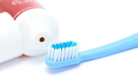 Blue toothbrush and tooth paste tube on white background. Closeup of the daily dental hygiene tool.の写真素材