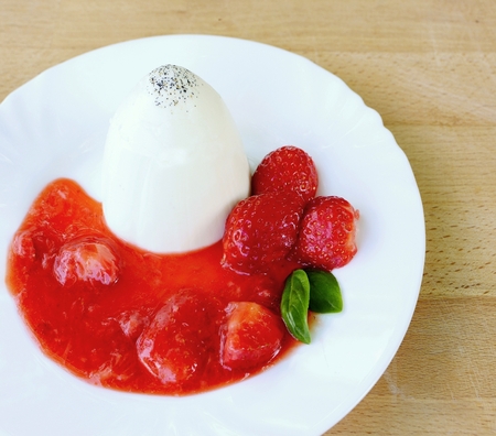 Panna Cotta with strawberries, strawberries sauce and basil leaves on white plate.の写真素材