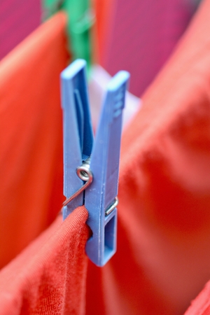 Clothespin on clothesline securing the red wet clothes. Red wet clothes drying on clothesline securing with clothespin.の写真素材
