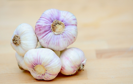 Bunch of fresh garlic with green scape on brown wood plate.の写真素材