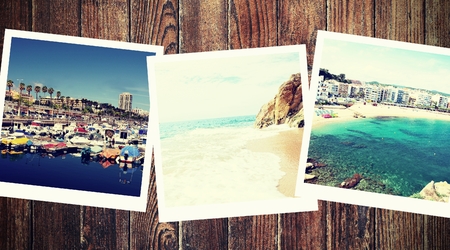 Vintage photos from summer holiday with traditional white frame placed on wooden desk.の写真素材