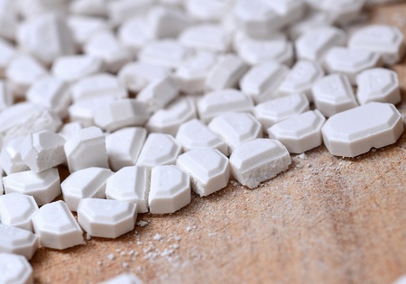 Macro of the white pills cut into pieces on wooden brown background.の写真素材