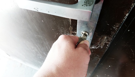 Close-up of hand with key unlocking the metallic door.の写真素材