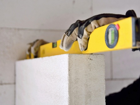 Building worker measuring the wall with a water level at construction site.の写真素材