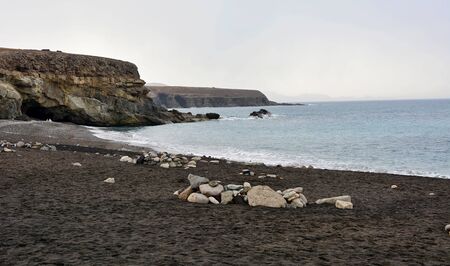 Beach with black sand near rocky coast in Ajuy village, Fuerteventura, Spain.の写真素材