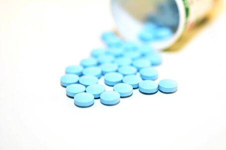 Closeup of a Blue Drug Pills Spilling Out of a Bottle on the White Background.の写真素材