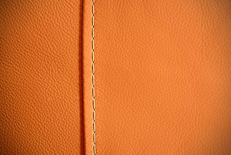 Full frame background texture of pebbled orange leather with one seam thread.の写真素材