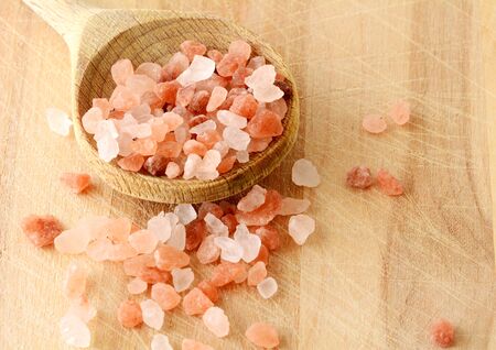 Scattered Pink Himalayan Rock Salt in Wooden Spoon on Wooden Background, top view.の写真素材