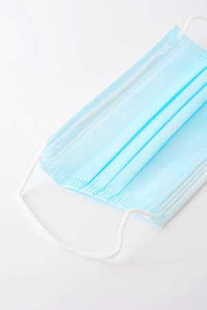 Blue surgical face mask (currently protecting against virus on white background.