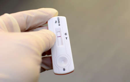 Hand in medical gloves is holding negative antigen rapid test for capturing of antibodies. It shows...