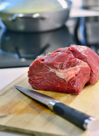 Raw beef meat and knife on the kitchen desk.