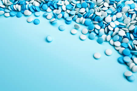 Blue and white coated chocolate candies scattered on blue background. 3d renderingの写真素材