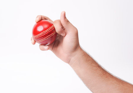 Closeup Photo Of A Male Bowler Firmly Gripping On A Red Test Match Cricket Ball On White Background