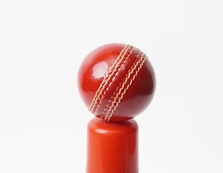 A Shiny New Test Cricket Ball Leather Hard Stitched Ball Placed On Top Of Red Cylindrical Objectの写真素材
