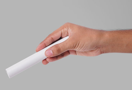 Closeup Photo Of A Male Hand Holding A New White PVC Plastic Pipe Isolated On Grey Backgroundの写真素材